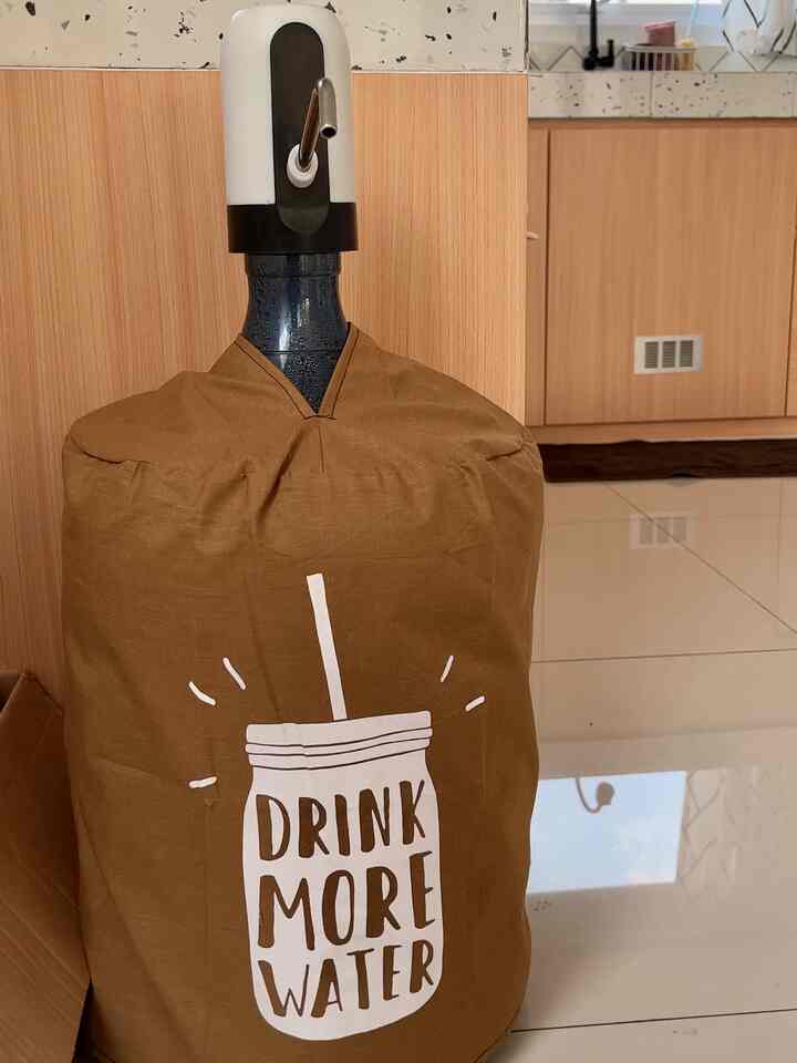 Kitchen scene showing a water gallon with brown fabric cover on a clean white tile floor with wooden cabinets in background