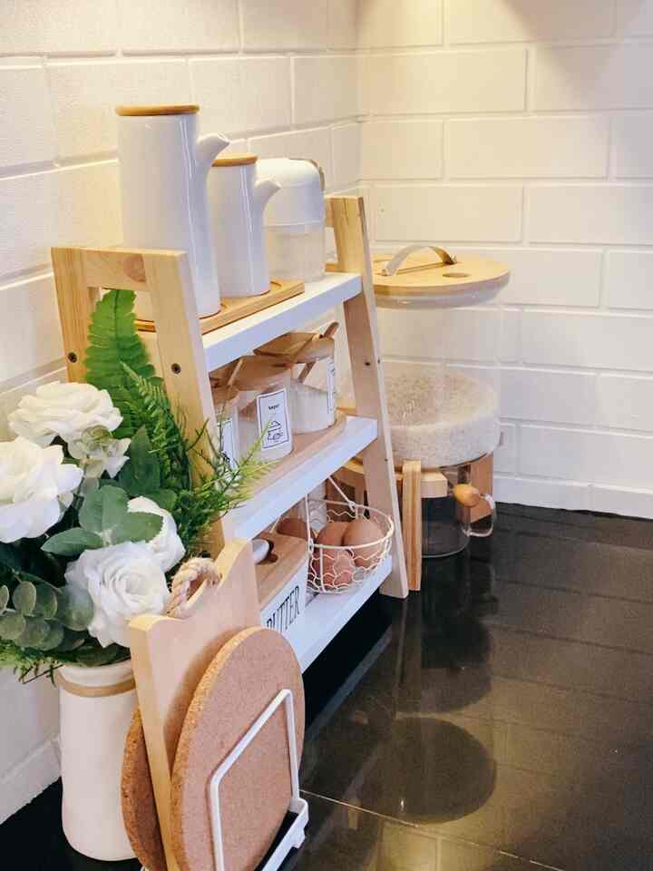 White walls and wood-toned shelving at kitchen corner, featuring neatly arranged storage items and tableware with a natural atmosphere