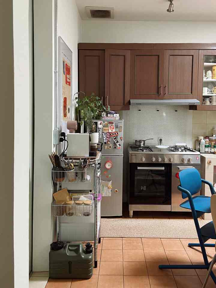 Brown kitchen cabinets and silver stainless steel appliances blend in kitchen space with arched entrance and varied kitchen storage elements