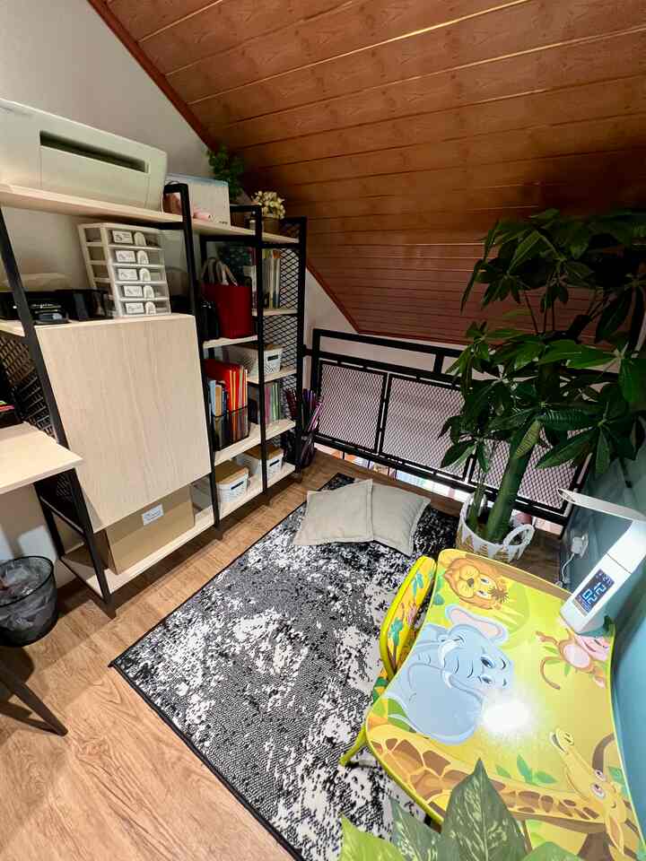 A wood-toned natural small loft home office space featuring a children's desk, bookshelf, and rug creating a cozy study room