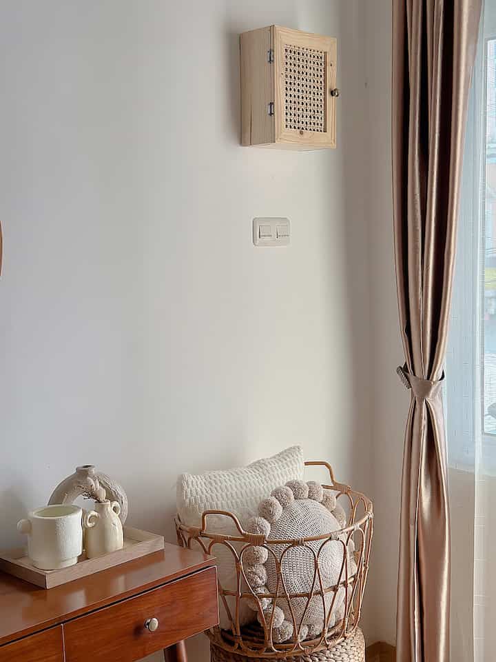 Beige-toned living room corner featuring wooden furniture and basket with cushions, creating a natural and cozy atmosphere