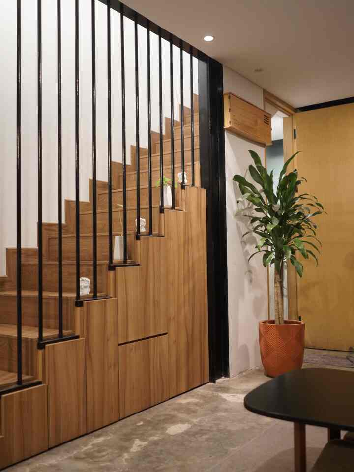 Natural wood-tone and black accented entrance featuring custom under-stair storage, modern and cozy atmosphere