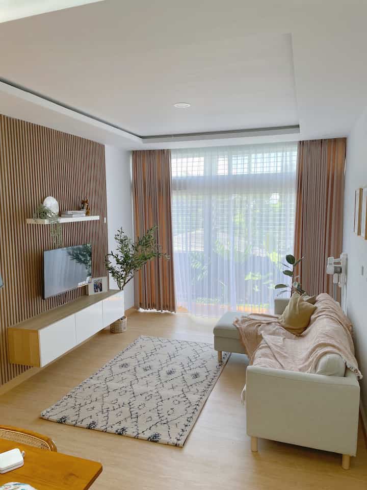 A cozy living room with warm wood tones and natural colors, featuring a beige sofa and patterned carpet