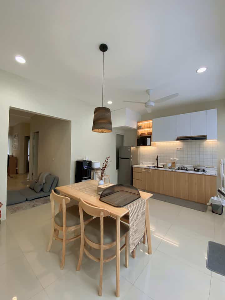 White and wood-tone compact kitchen and dining table in an open space interior
