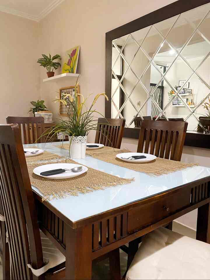 Natural wood-tone simple dining room for four featuring a large mirror enhancing spaciousness
