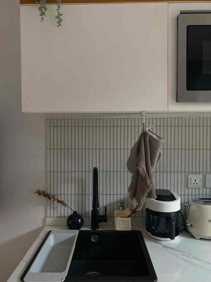 White-toned kitchen featuring a black sink and faucet, with a digital air fryer creating a clean and minimal space