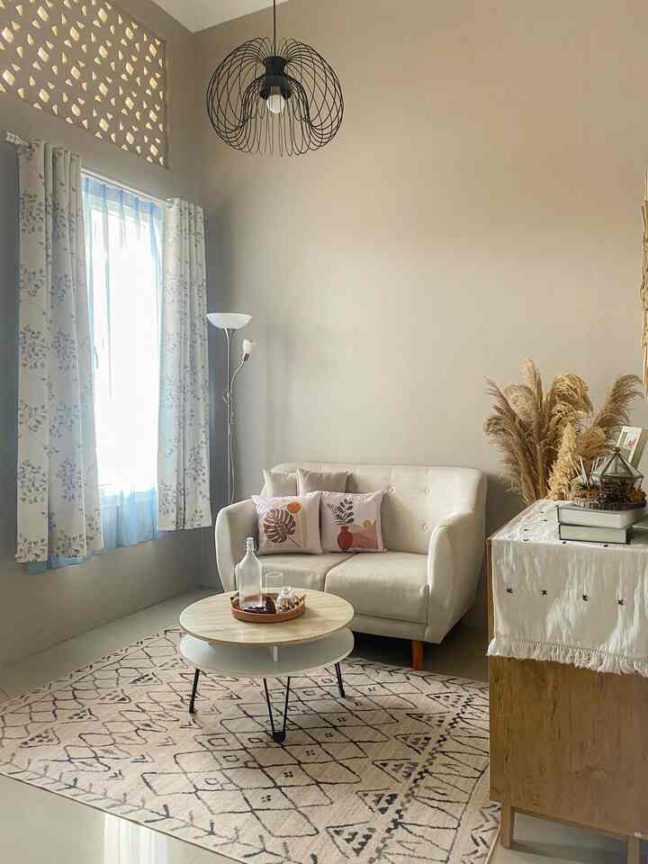 Light brown toned living room featuring a beige sofa, patterned rug, and floral curtains creating a cozy atmosphere