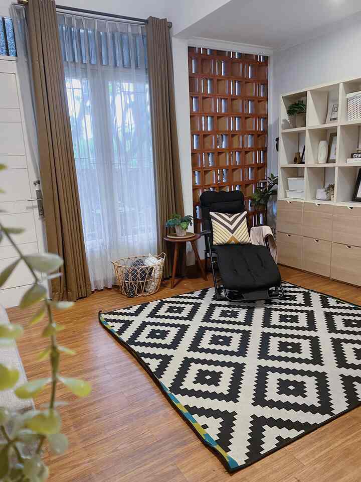 Natural wood tones and modern rug in a 4x6.5m living room featuring a comfortable recliner and calm curtains