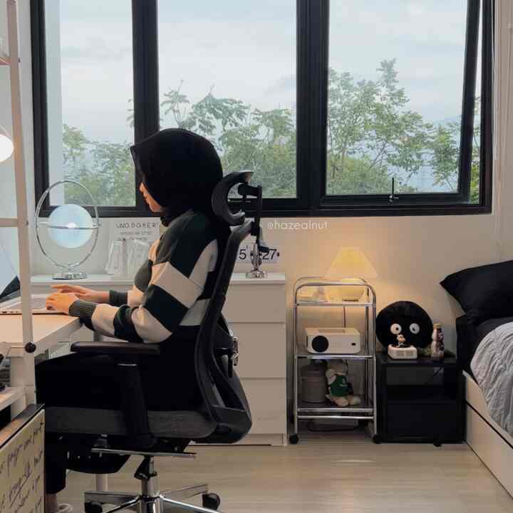 White and black toned bedroom home office featuring ergonomic office chair and desk with cozy atmosphere