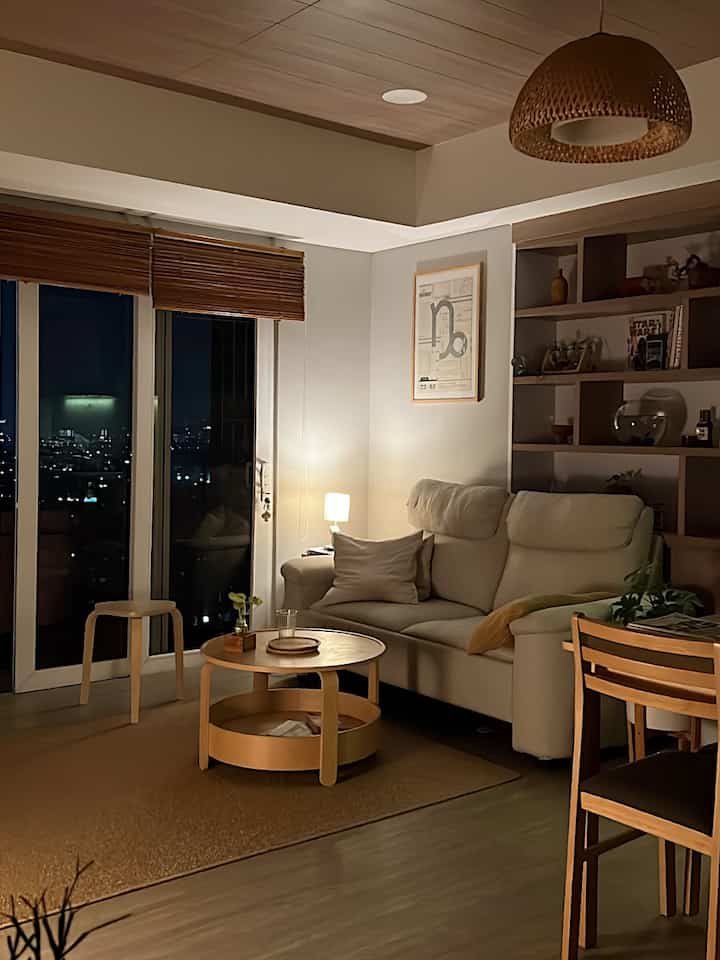 Natural wood tones and white walls in a living room, bright sofa and round coffee table create a cozy nighttime atmosphere