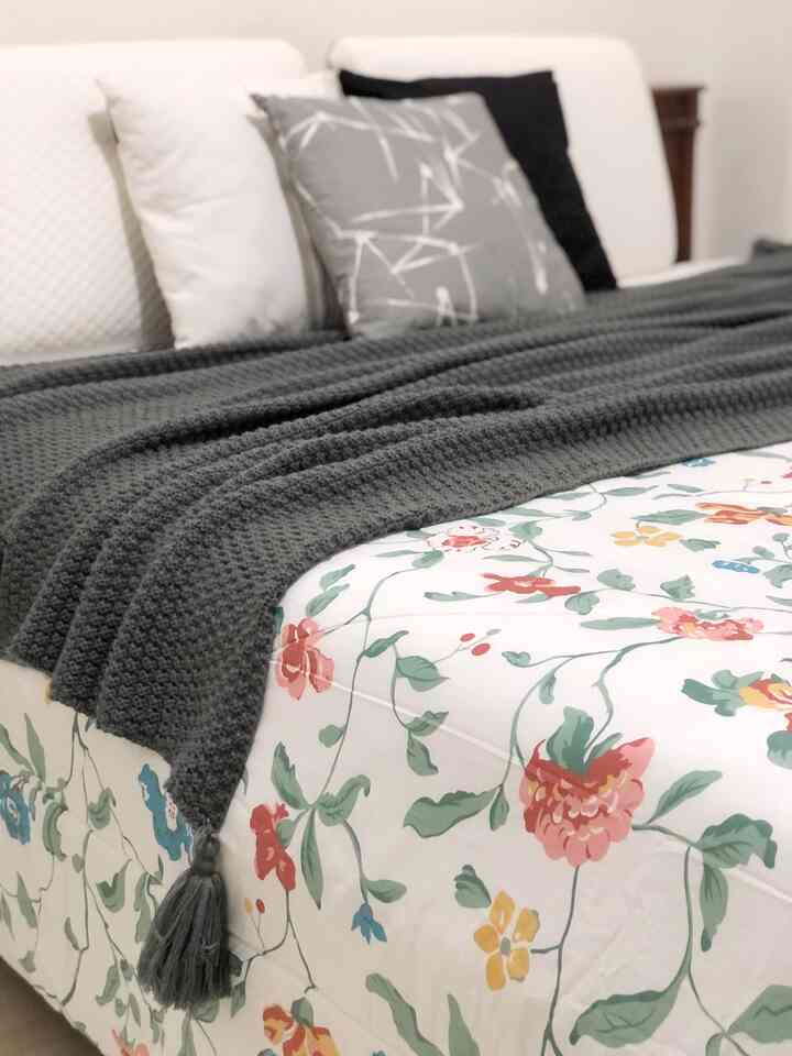 Gray and white toned bedroom featuring floral bedding and cozy pillows with a calm atmosphere