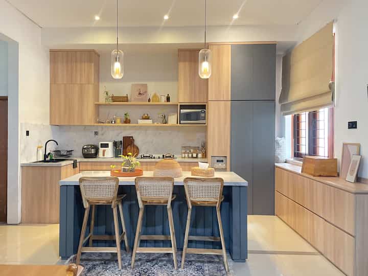@kns.living Kitchen in wide angle ✨
-
Kitchen room ini ukurannya 4.3 x 4.3 m, dengan panjangan island table 2m yang ada di center sebagai vocal point dapur kami.
-
Disini aku pakai 2 lighting lampu dari lampu gantung dan juga down light dengan 3 titik lampu. Aku menambahkan 3 stool chair yang aku custom dengan rattan sebagai pemanis dengan warna yang mirip dengan cabinet kitchen. Warna yang aku pilih kayu natural tujuan nya agar senada dengan interior ruang lainnya. Karpet di tengah bar stool aku pilih dengan warna senada juga dengan kitchen cabinet, yaitu perpaduan warna cream dan abu2.
-
Aku juga custom cabinet yang ada di sisi kanan, untuk menempatkan perkakas dapur dan menyimpang barang lain dirumah. Jadi di dapur ini kami maksimalkan ruang nya untuk menyimpan segala kebutuhan rumah kami agar tertata lebih rapih😊✨
-
#KNSLiving
#Homedecoration
#KitchenDecoration
#KitchenRoomDecor
#DiningRoomDecor 
#KitchenIdeas
#DiningRoomIdeas
#KitchenInspiration
#DiningRoomInspiration
#KitchenStyling
