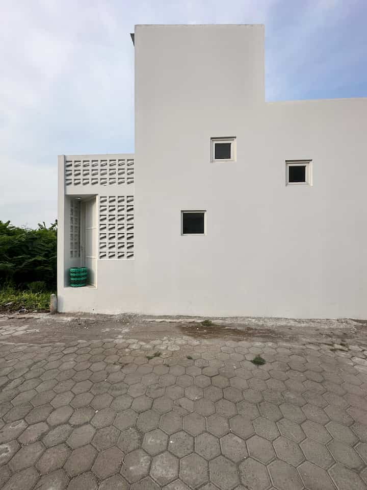 White-toned minimal contemporary house facade featuring square windows and perforated concrete blocks for aesthetic and ventilation