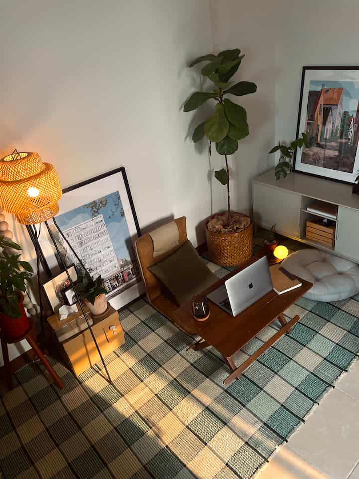 Natural brown and beige toned studio living room featuring floor cushions, foldable chair, and wooden table with cozy atmosphere