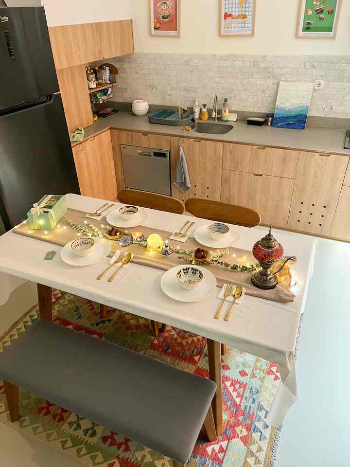 Bright white tablecloth on wooden dining table in kitchen-dining room featuring simple festive decorations and 4-person place settings
