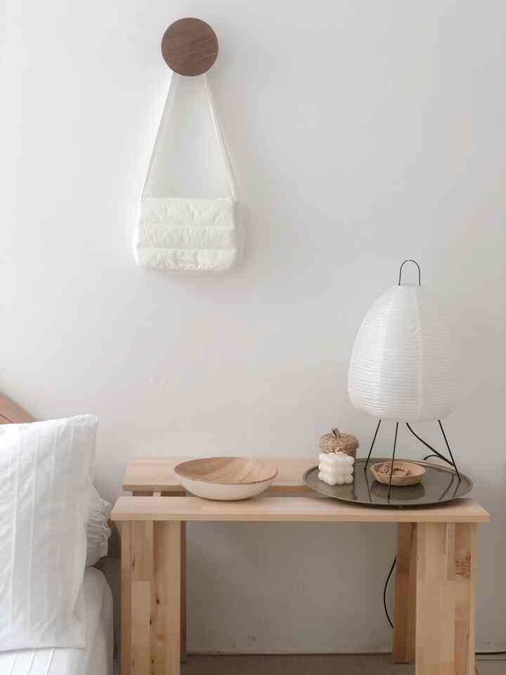 A simple and natural bedroom in white and wood tones featuring a side table and a Japanese-style table lamp with a clean aesthetic