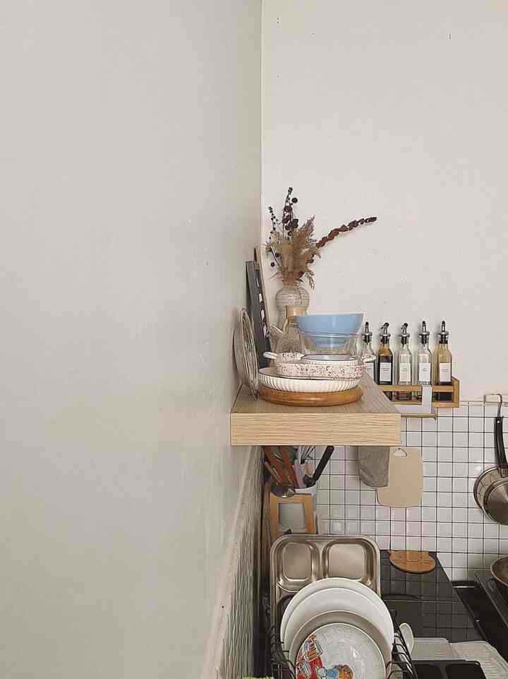 Natural tones and white kitchen corner featuring shelves and neatly stored tableware in a practical space