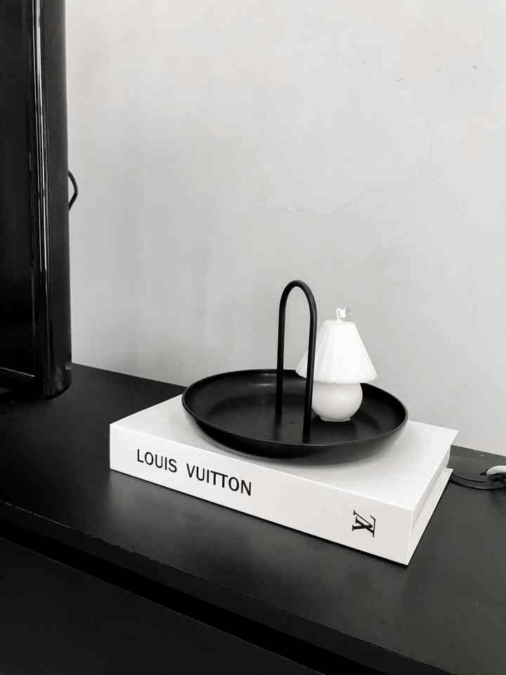 Monotone living room space featuring a black table with a white book and black round tray in a simple interior