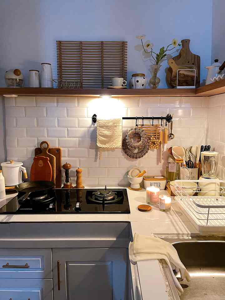 Cozy kitchen space featuring white tiles and wood-tone cooking utensils, with lighting and candles enhancing the ambiance