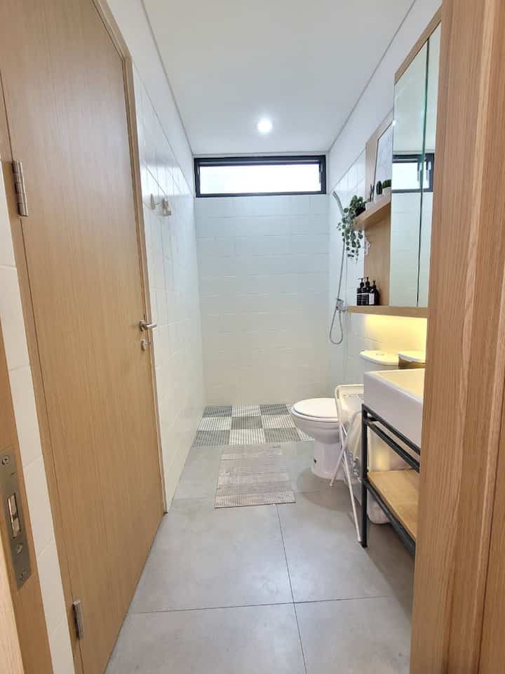 Compact bathroom featuring white tiles and natural wood tones with a minimalist atmosphere
