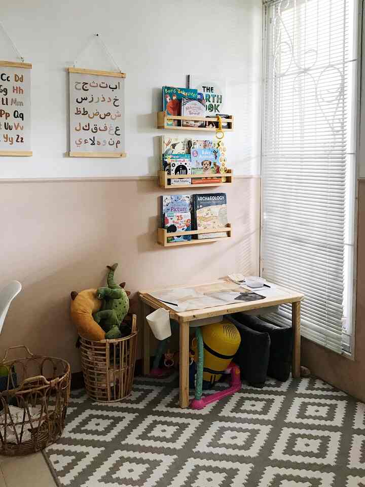Beige lower walls and white upper walls of a cozy kids' room with natural wood furniture and children’s bookshelves