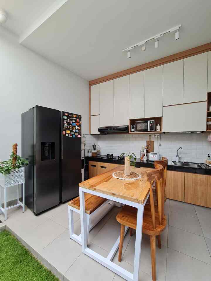 Natural toned compact kitchen featuring wooden dining table and white cabinets with practical design