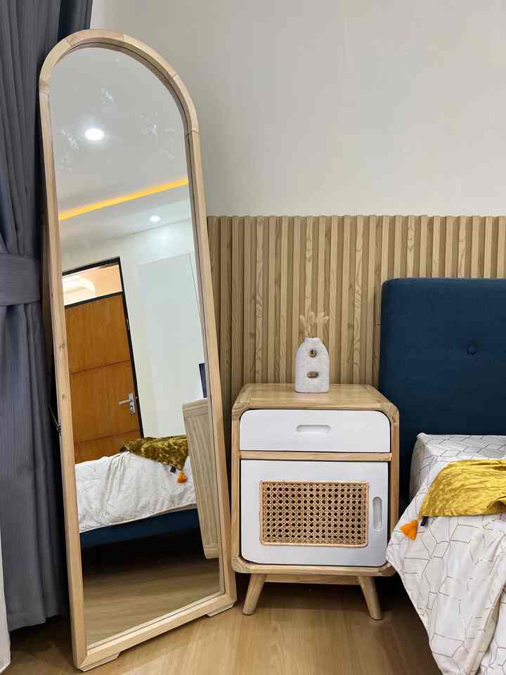 Natural wood tone and blue bedroom with full-length mirror and nightstand, creating a cozy and simple space