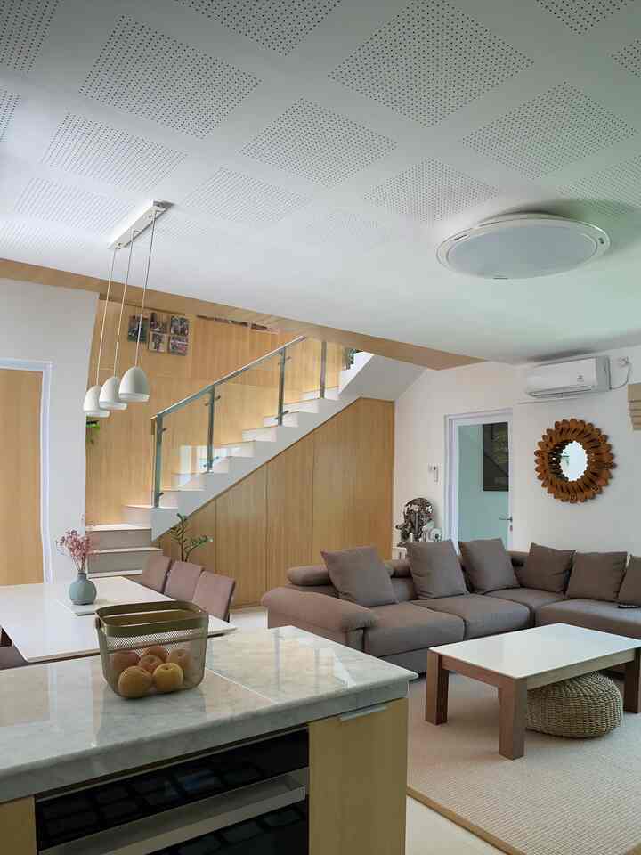Bright wood tones and white colors define this modern living and dining room featuring an L-shaped sofa and pendant lighting with a warm atmosphere