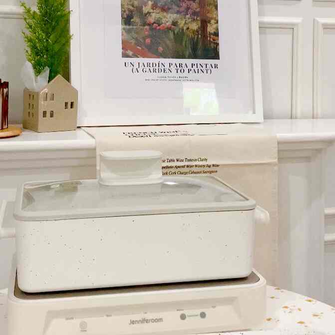 White-toned kitchen space featuring a minimalistic multigrillpan and framed art piece, presenting a clean interior