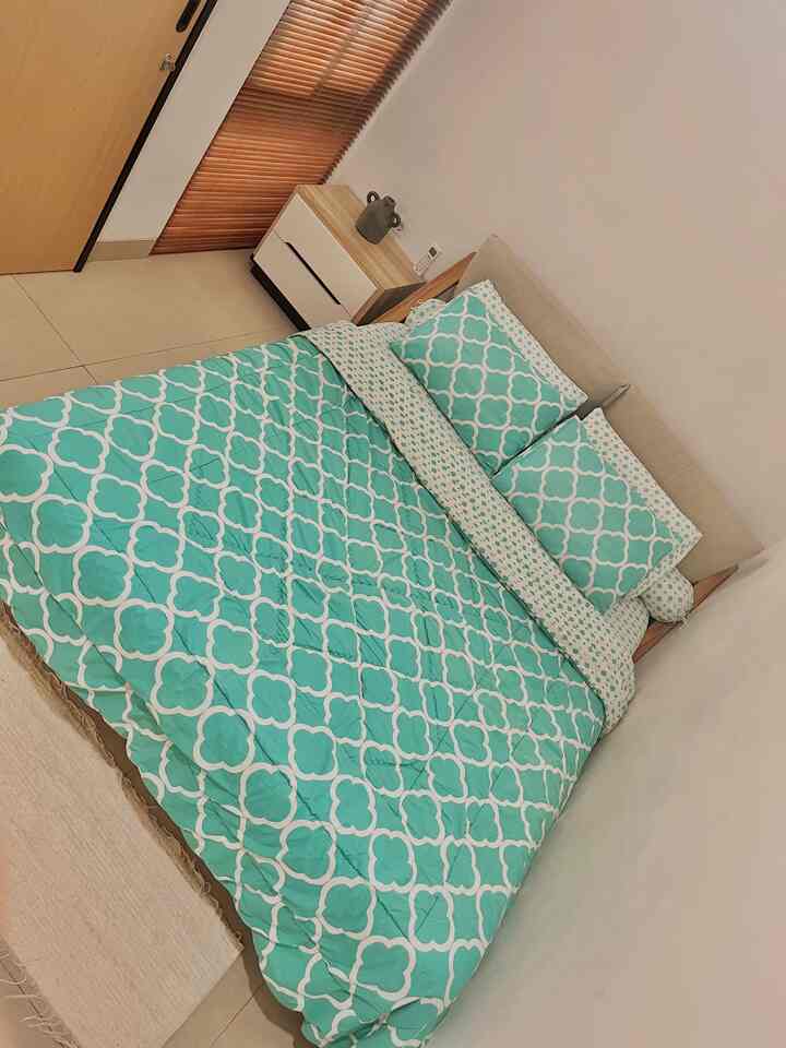 Natural white and brown toned bedroom featuring a patterned bed centrally placed with wood blinds, creating a simple space