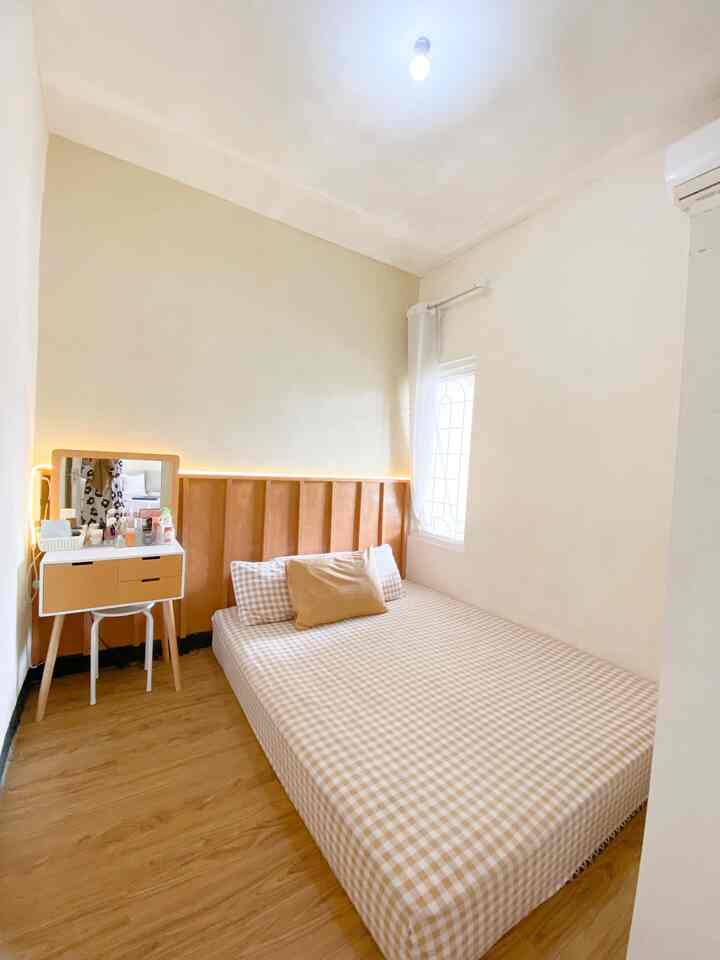 Beige and white toned bedroom featuring a gingham patterned bedspread and wood tone flooring with a simple, cozy atmosphere