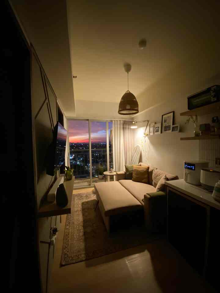 Beige and wood-toned cozy studio living room featuring a sofa and pendant light with a warm atmosphere