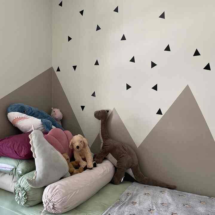 Natural-colored kids' room featuring beige geometric wall patterns and a collection of various animal plush toys creating a cozy atmosphere