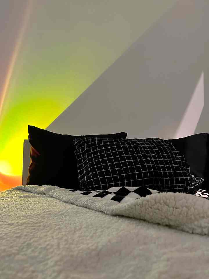 White and black toned bedroom featuring a bed with checkerboard throw and warm mood lighting creating a cozy atmosphere