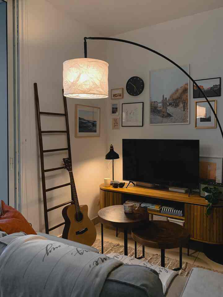 White-walled living room with natural wood tones and black accents, featuring a sofa and round coffee tables in a cozy setting