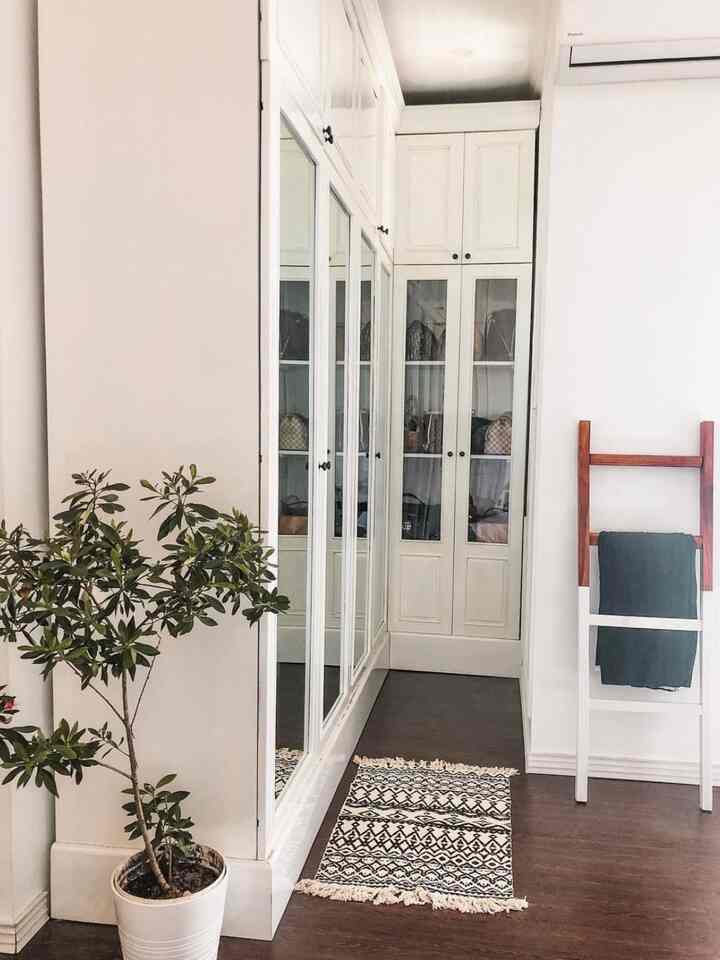 Bright white-walled bedroom corner with wood-toned flooring and large built-in storage cabinets, creating a natural and clean ambiance