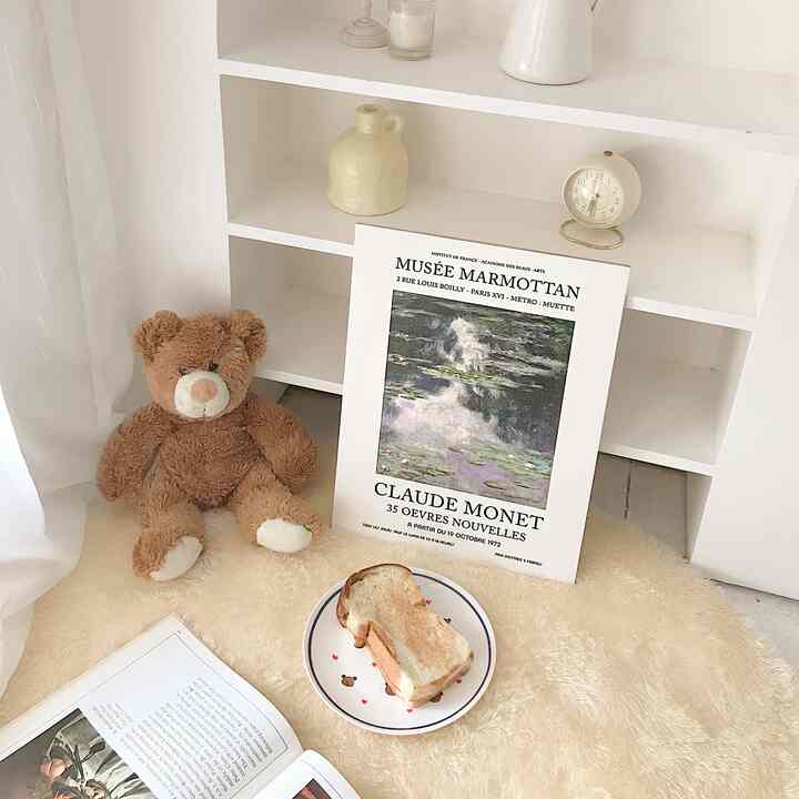 Beige and brown toned living room corner featuring a plush teddy bear, Claude Monet poster, and cozy rug with simple decor