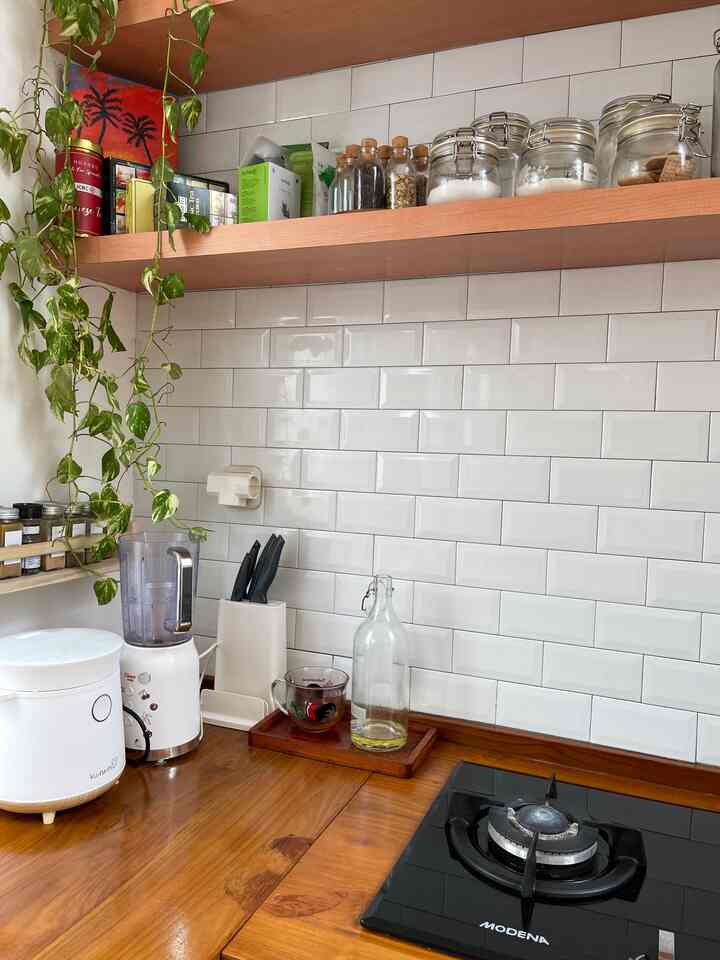 White tiled wall and wood tone kitchen counter with knife block and kitchen utensils in a clean Japandi style kitchen