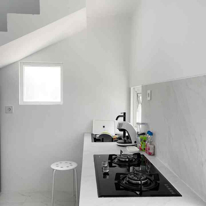 White-toned kitchen space featuring a gas stove and a simple stool in a clean and minimal setting