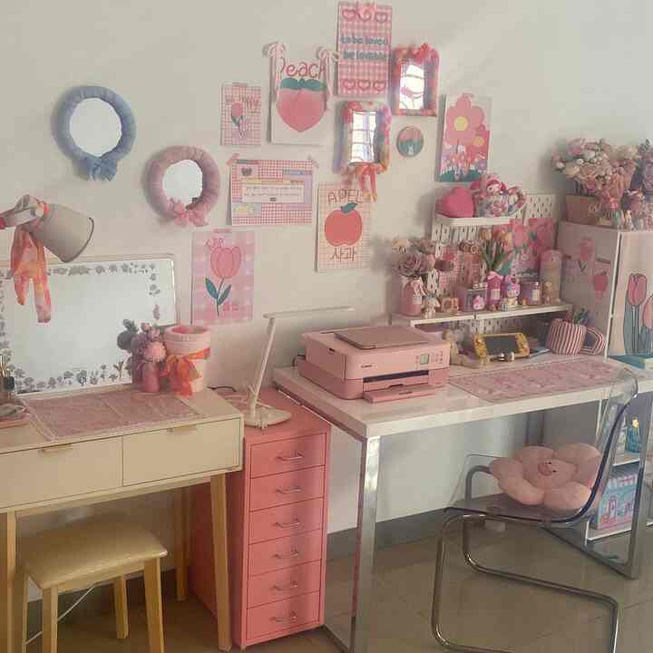 Pink-toned study and vanity area featuring desks, pink storage cabinet, floral cushions, and decorative wall art