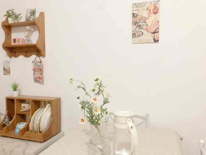 White-walled dining room with brown wooden shelves and dining table for two, featuring a natural and simple atmosphere