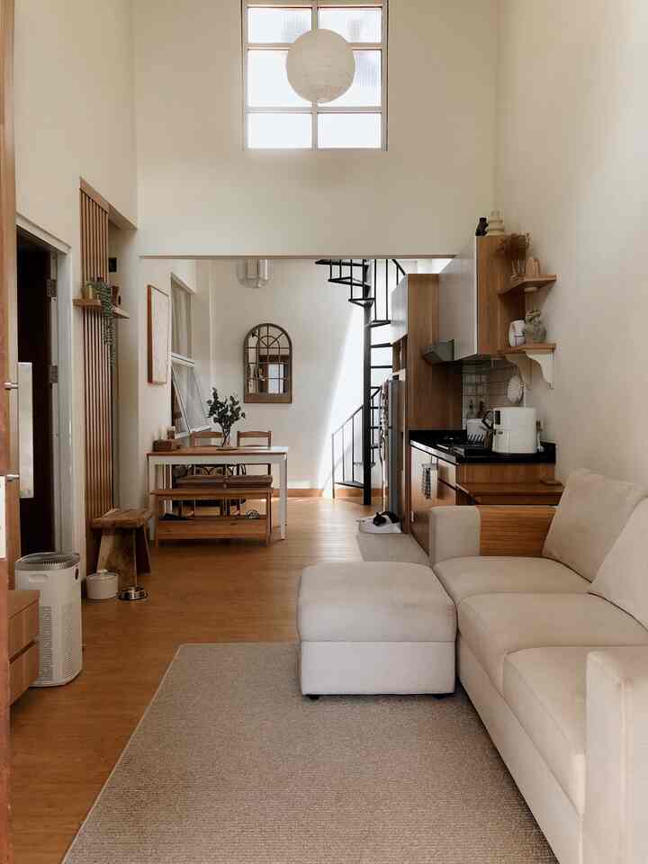 Natural-toned long and narrow living room and kitchen featuring beige sofa and wood-toned furniture creating a warm atmosphere