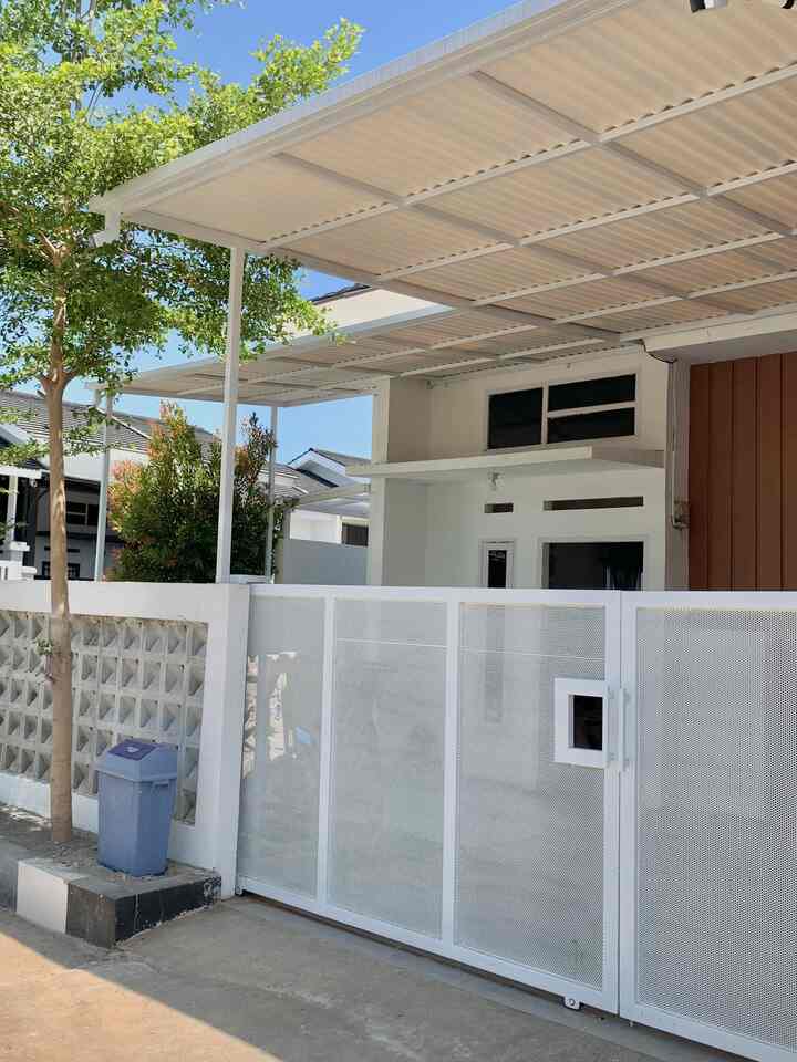 White and gray toned house entrance featuring a perforated metal gate and Alderon RS roofing, showcasing a simple, modern facade