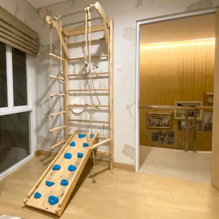 Natural wood tone and white colored small kids' room featuring play equipment centrally placed, bright and cozy space