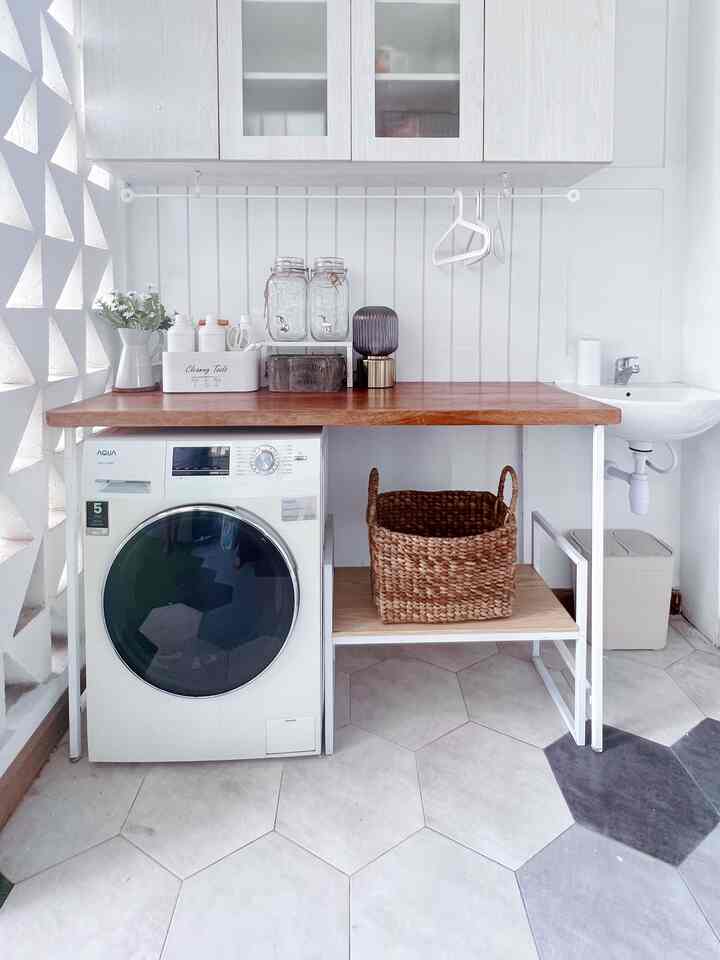 Bright white and wood tone rooftop laundry room with front-loading washing machine and wicker basket in a compact, narrow layout