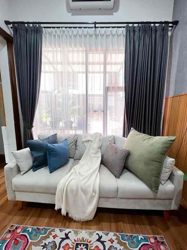 White and gray toned living room featuring a beige sofa with various cushions and a throw blanket creating a cozy atmosphere