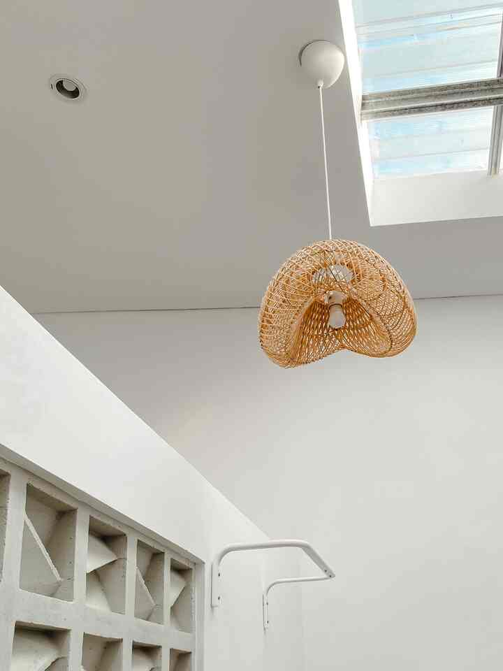 Compact vertical laundry space with white walls and ceiling, featuring a rattan pendant light