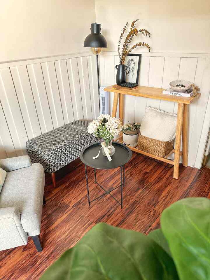Natural-toned compact living room featuring a wooden console table and black floor lamp with cozy accents