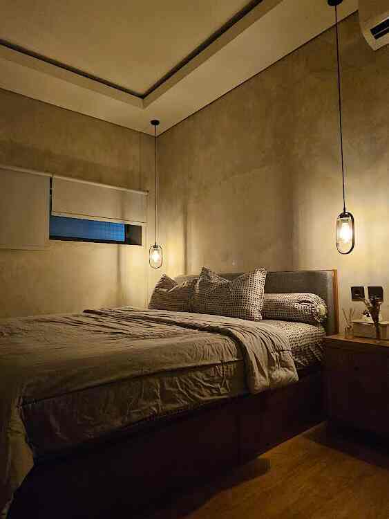 Kamar utama berukuran 4x3 m ini masih mengusung tema industrial minimalis dgn dinding semen expose tanpa hiasan apapun di dinding.
Agar kamar lebih nyaman, dipasang 2 buah lampu gantung di sisi kanan & kiri tempat tidur shg memberikan vibes yg berbeda. 
Kamar ini lebih didominasi dgn furniture kayu jati yg dibuat custom krn menyesuaikan dgn ukuran ruangan & ketahanan jati yg sdh dikenal kuat & tahan lama.
Untuk lantai menggunakan SPC dgn motif kayu juga.

#cozybedroom #dekorasikamartidur #inspirasikamartidur  #industrial #industrialhouse