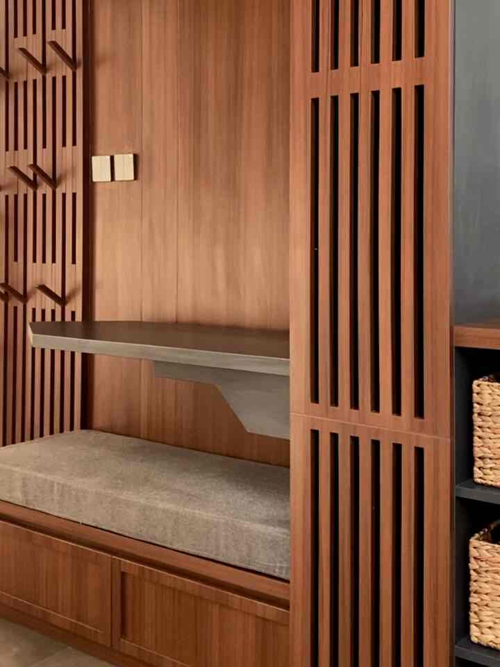 Warm natural wood tone laundry room bench with beige cushion in a simple Japandi style multifunctional space